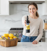 Woman holding a bottle of wipe right lemon-aid in a kitchen with lemons and lavender on the counter.